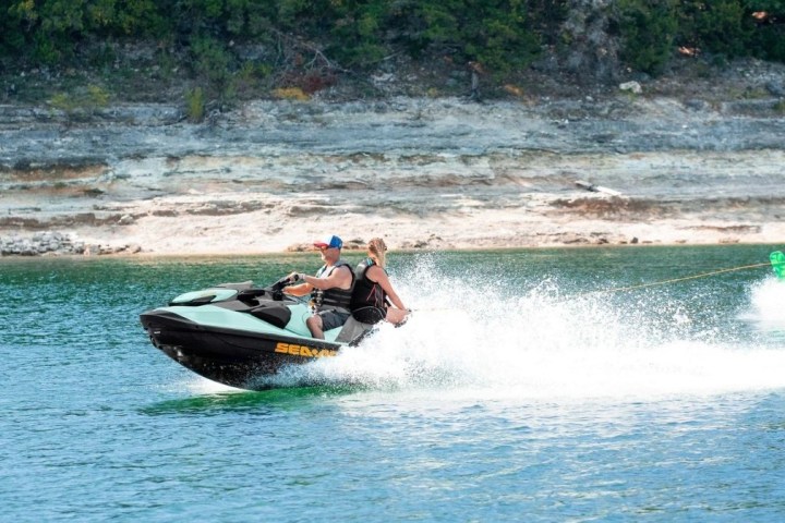 a man riding on the back of a boat in the water