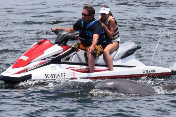 a man riding on the back of a boat in the water