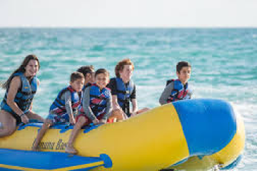 Group of people riding a banana boat on the ocean.