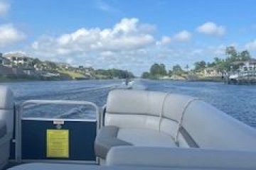 View from a boat on a river with blue sky and houses along the banks.