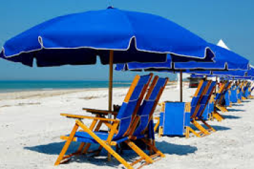 Line of blue beach umbrellas and chairs on a sandy shore.