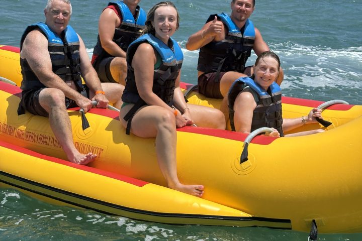 Five people in life vests on a yellow inflatable boat in the ocean.