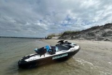 Jet ski on a sandy beach with cloudy sky overhead.