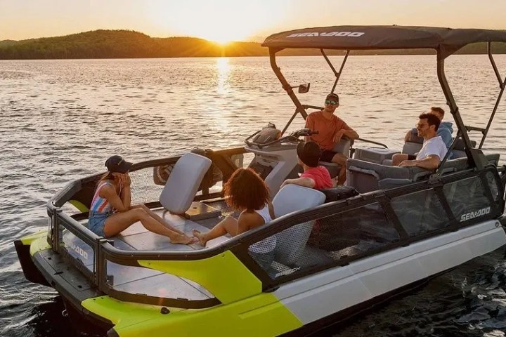 Group of people relaxing on a boat at sunset on a calm lake.